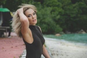 Elegant portrait of a woman in a swimsuit by the beach, showcasing natural beauty and style.