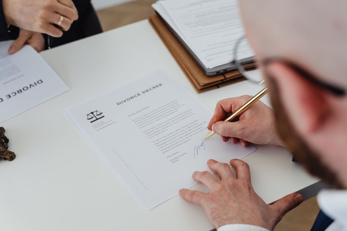 Homme en train de signer un document à une table de bureau