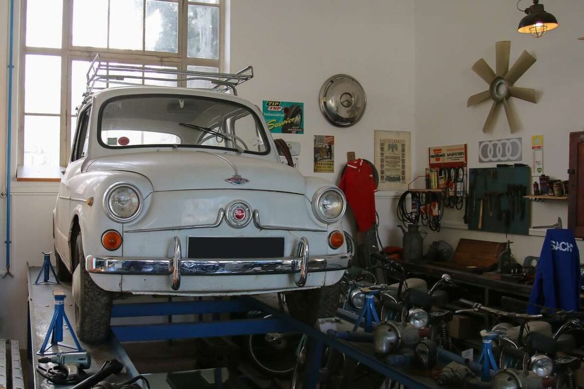 Voiture blanche vintage sur pont d'atelier, outils et pièces autour