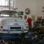 Voiture blanche vintage sur pont d'atelier, outils et pièces autour