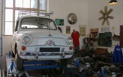 Voiture blanche vintage sur pont d'atelier, outils et pièces autour