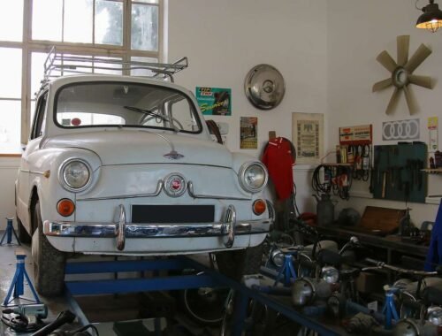 Voiture blanche vintage sur pont d'atelier, outils et pièces autour