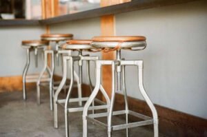 Rangée de tabourets de style industriel avec pieds métalliques et assises en bois clair, évoquant un atelier