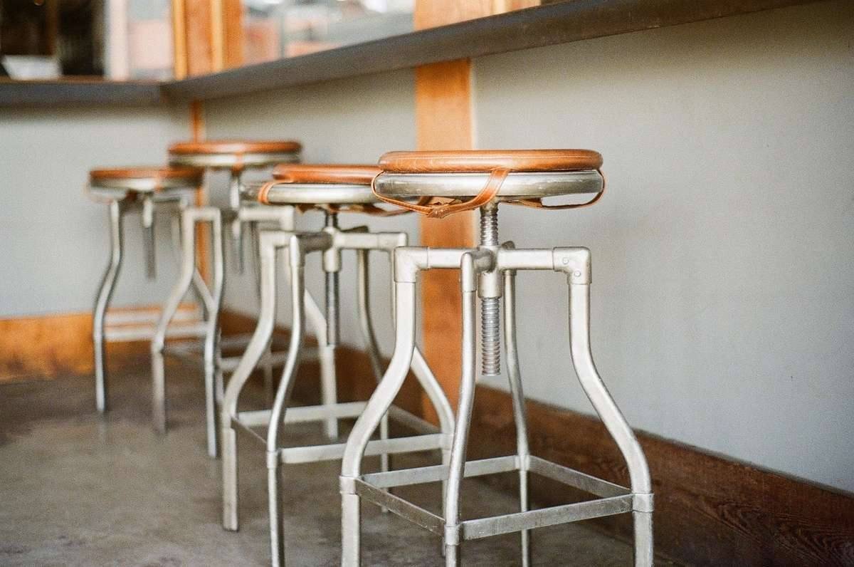 Rangée de tabourets de style industriel avec pieds métalliques et assises en bois clair, évoquant un atelier