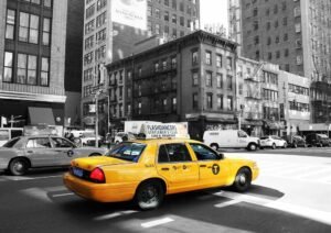 Taxi jaune circule dans une rue de la ville, entourée de bâtiments