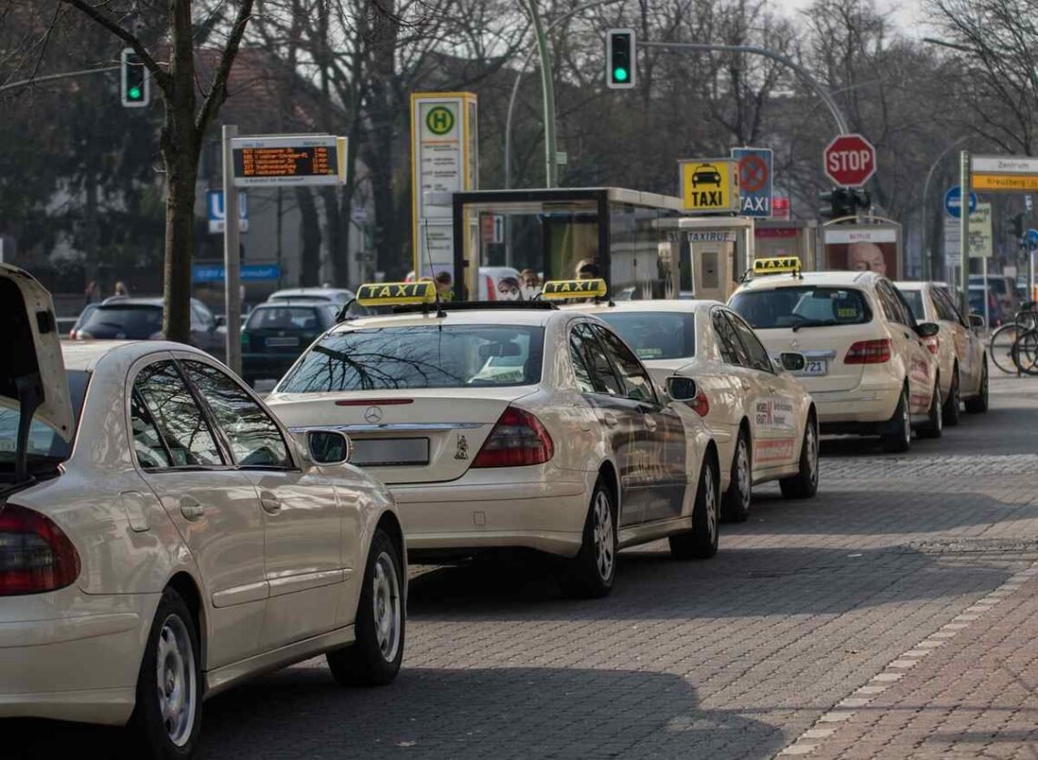 Une file de taxis et voitures attend au feu vert sur la rue