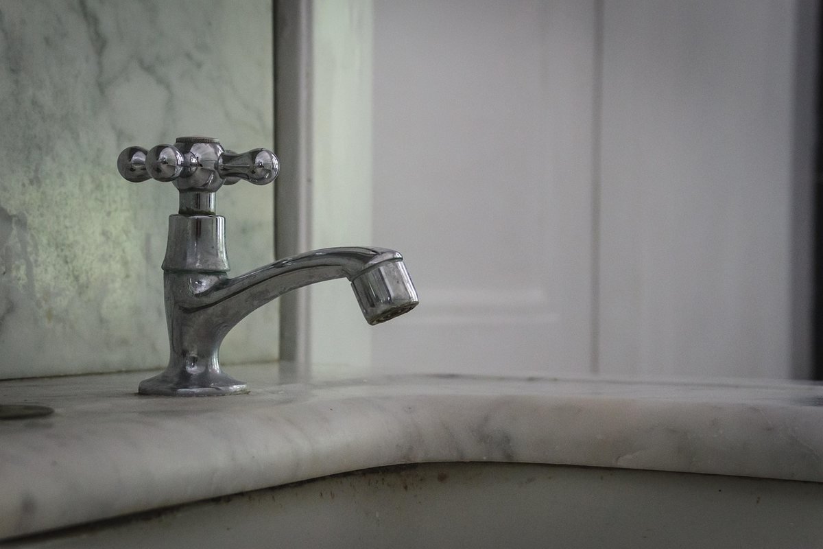 Un robinet à poignée croisée sur un lavabo en marbre