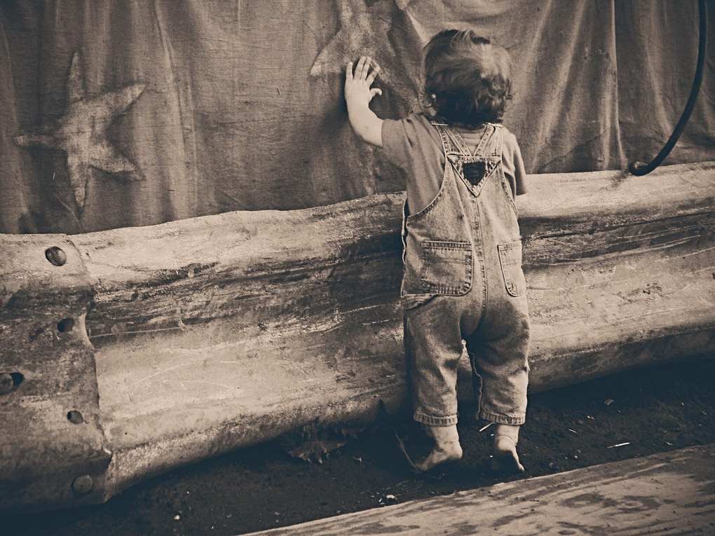 Enfant en surallures explore un mur étoilé derrière une barrière en bois