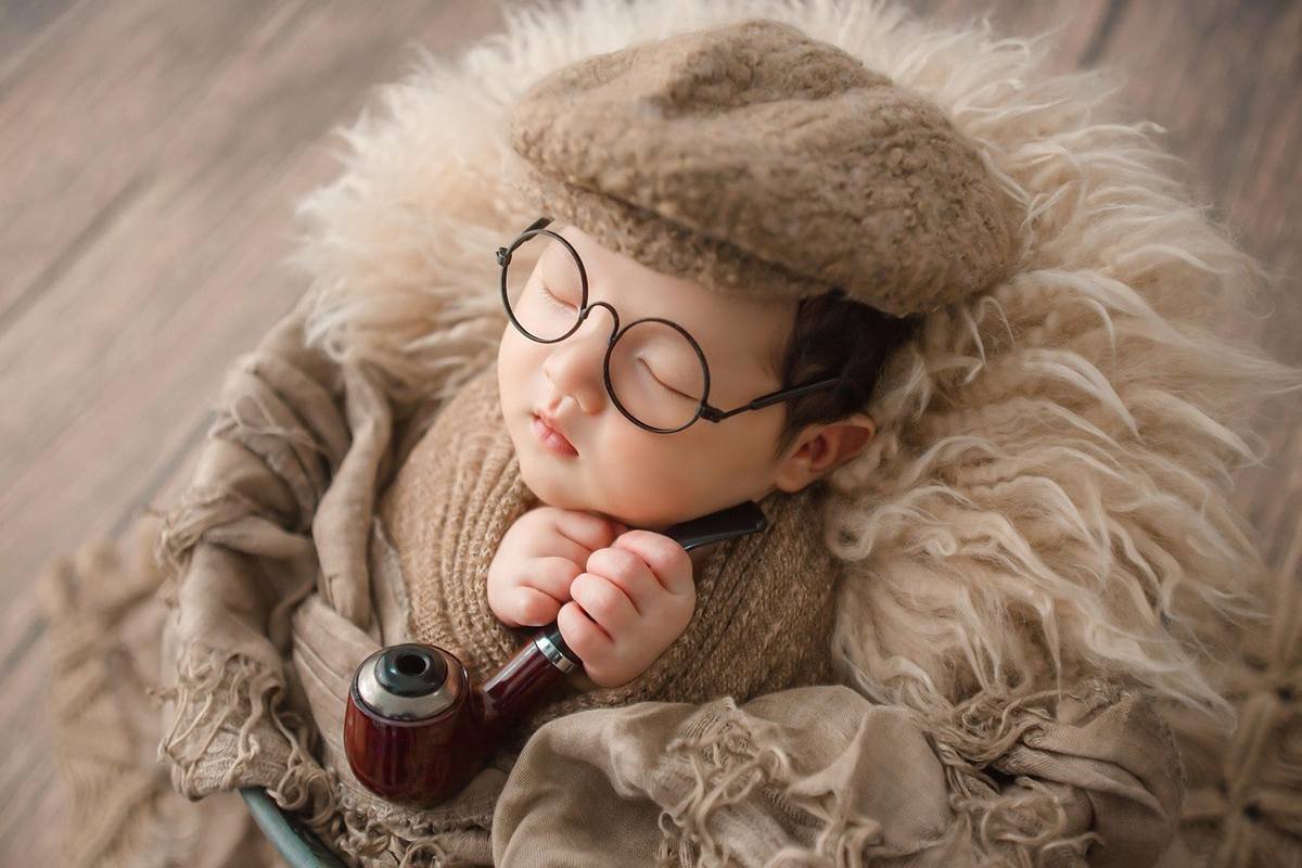 Enfant endormi avec chapeau, lunettes et pipe, entouré de fourrure sur fond en bois