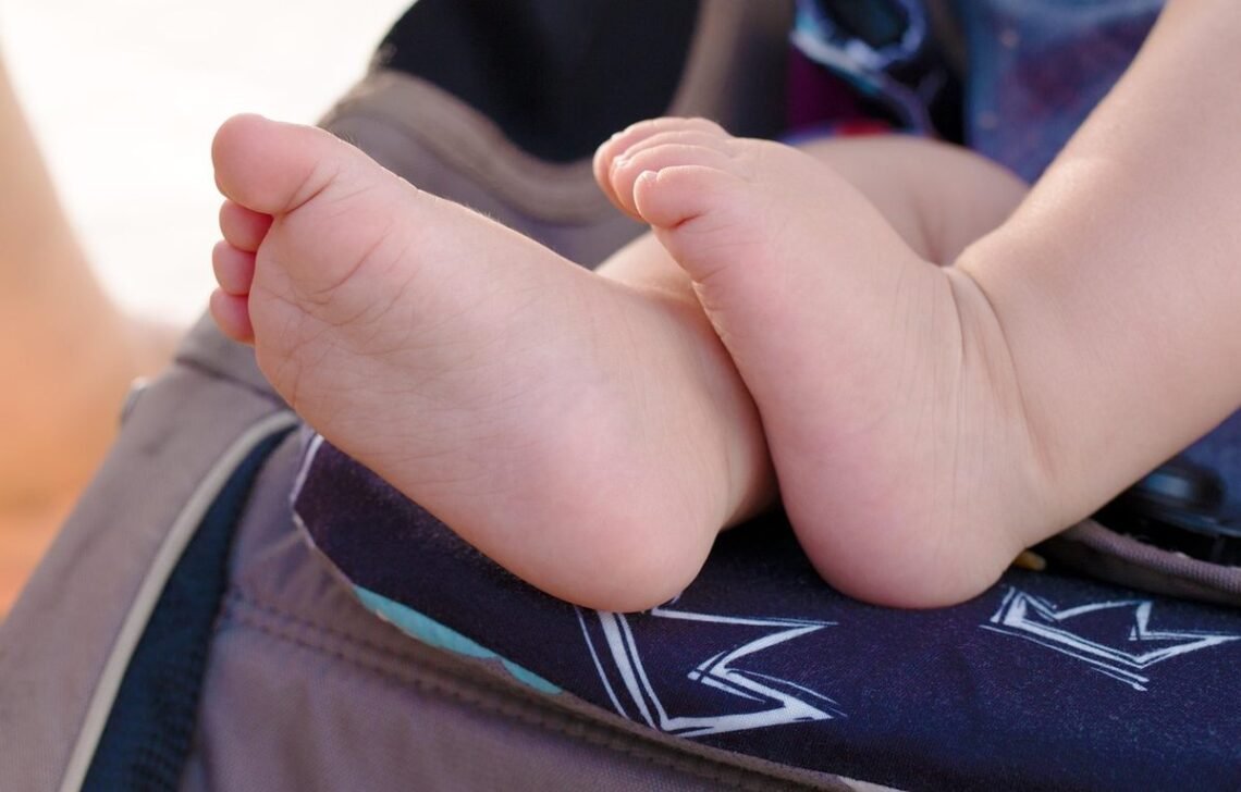 Pieds d'enfant sur un siège de poussette avec motif de couronne