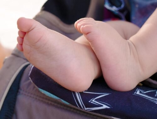 Pieds d'enfant sur un siège de poussette avec motif de couronne