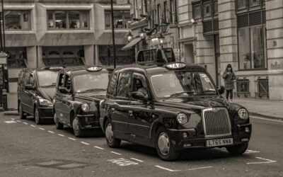 Des taxis noirs en rangée sur une rue de ville, piéton à droite