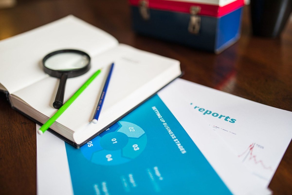 Carnet ouvert avec stylo et crayon, loupe, documents et rapport sur une table