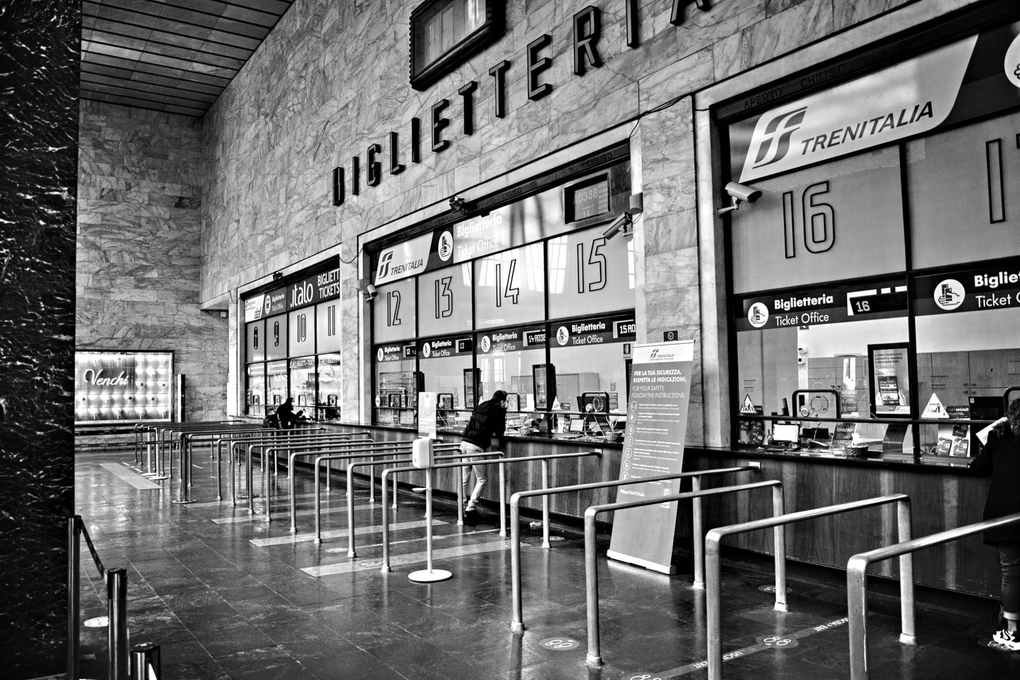 Salle de billetterie avec guichets numérotés et personnes en file d'attente
