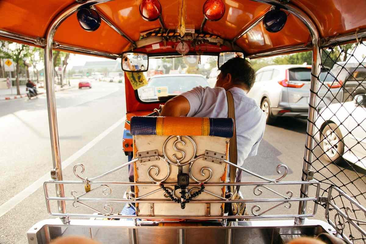Chauffeur de tuk-tuk assis, vue arrière du véhicule sur la route