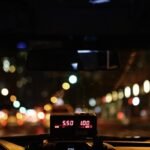 Compteur de taxi illuminé affichant le tarif nocturne sur une route urbaine avec bokeh lumineux