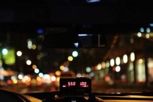 Compteur de taxi illuminé affichant le tarif nocturne sur une route urbaine avec bokeh lumineux