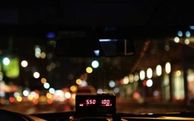 Compteur de taxi illuminé affichant le tarif nocturne sur une route urbaine avec bokeh lumineux