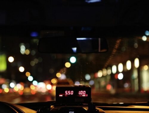 Compteur de taxi illuminé affichant le tarif nocturne sur une route urbaine avec bokeh lumineux