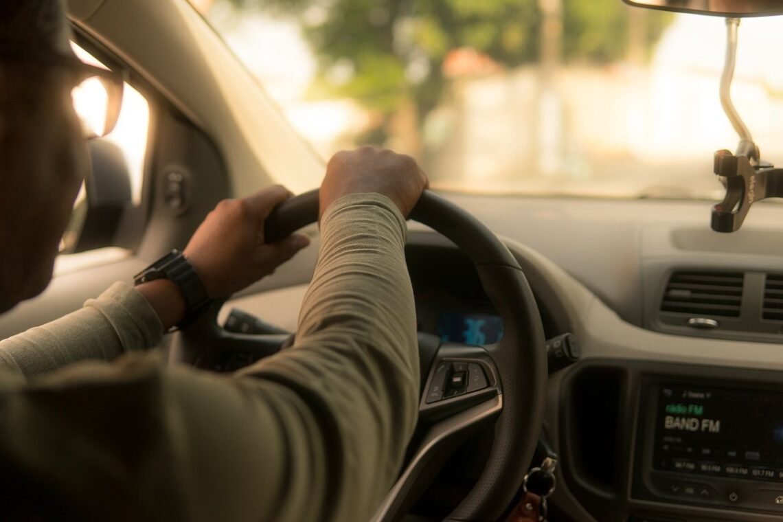 Un conducteur tient le volant à l'intérieur d'une voiture