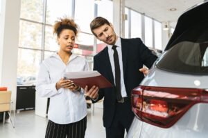 Professionnels discutant d'un dossier devant une voiture dans un showroom