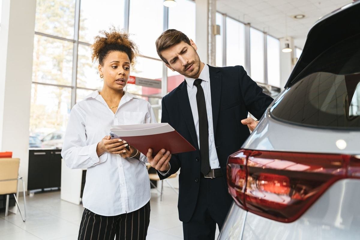 Professionnels discutant d'un dossier devant une voiture dans un showroom
