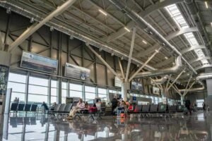 Intérieur d'aéroport avec voyageurs assis et écrans d'information