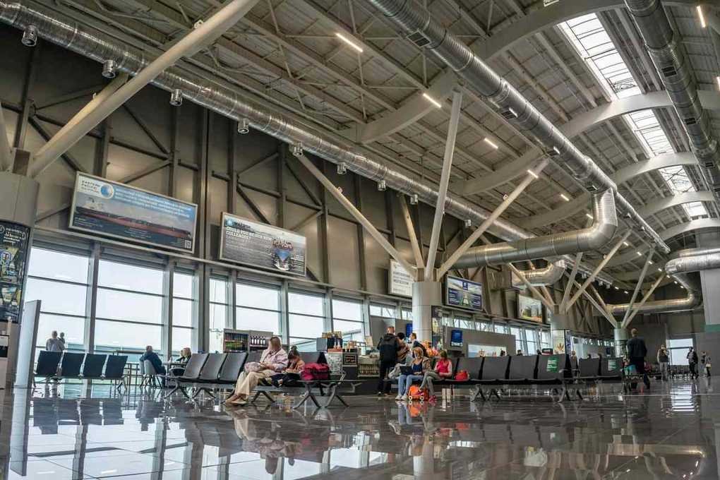 Intérieur d'aéroport avec voyageurs assis et écrans d'information