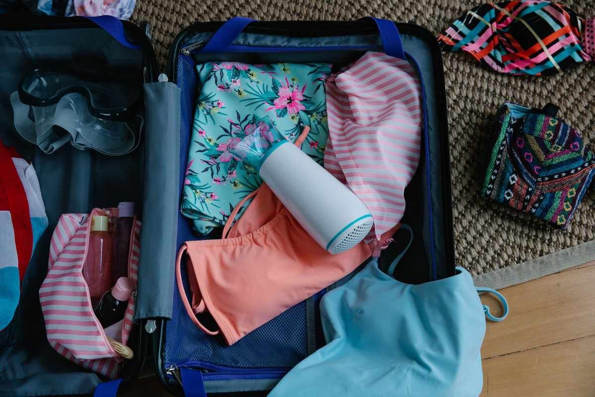 Sac à dos ouvert sur le sol, vêtement, bouteille, accessoires de plage