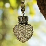 Un pendentif cœur en pierres orné d'une couronne suspendu à une chaîne