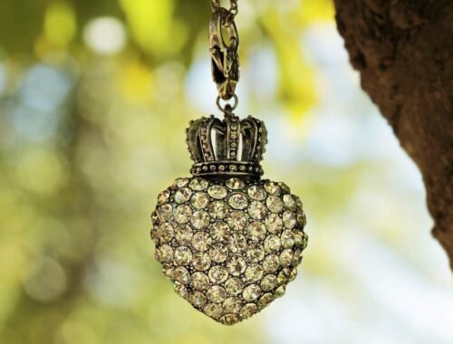 Un pendentif cœur en pierres orné d'une couronne suspendu à une chaîne