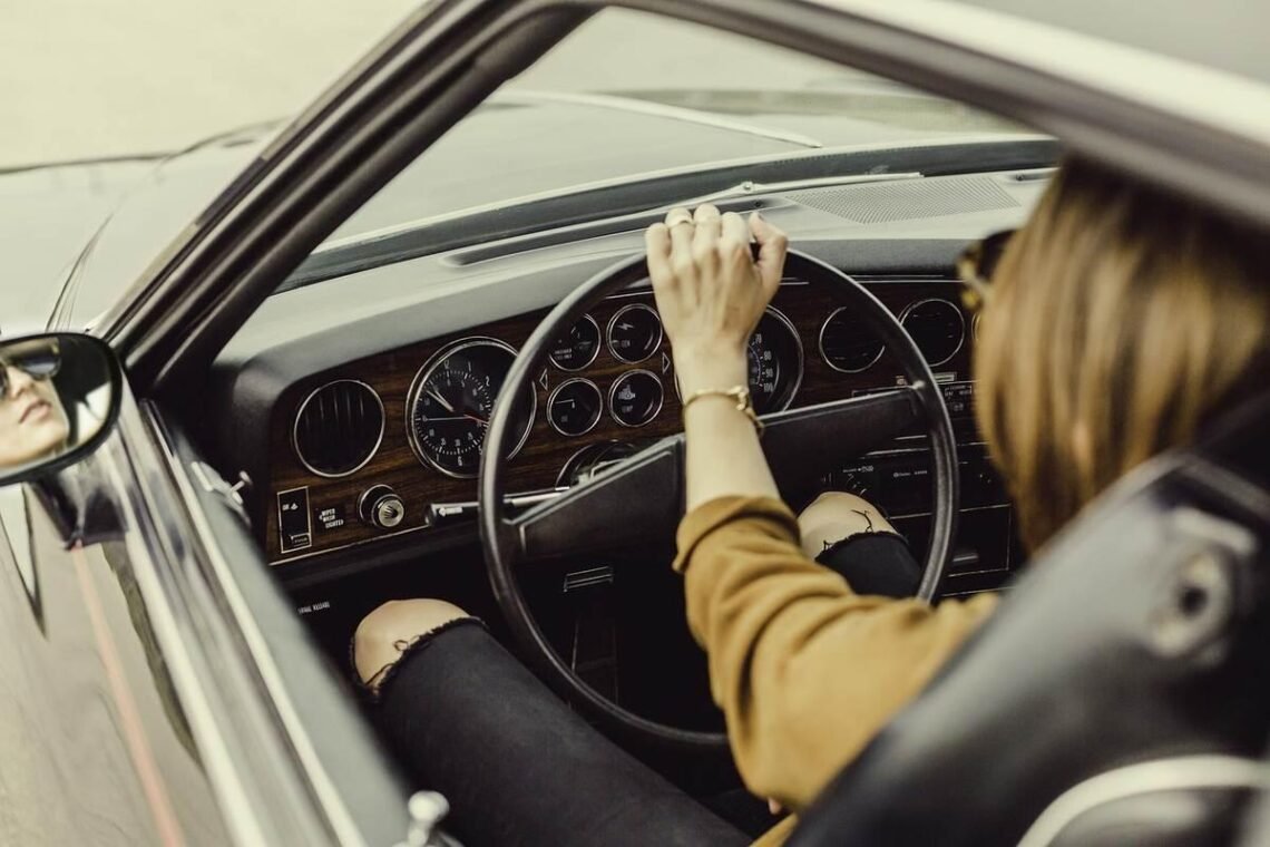 Femme au volant d'une voiture ancienne, main sur le volant en train de conduire