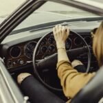 Femme au volant d'une voiture ancienne, main sur le volant en train de conduire