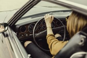 Femme au volant d'une voiture ancienne, main sur le volant en train de conduire