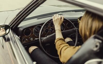Femme au volant d'une voiture ancienne, main sur le volant en train de conduire