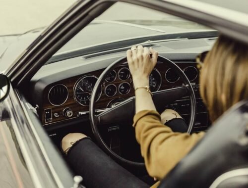 Femme au volant d'une voiture ancienne, main sur le volant en train de conduire