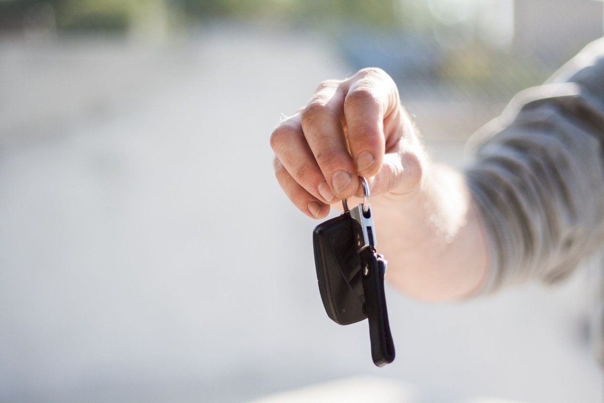 Main tendue présentant des clés de voiture noires avec porte-clés