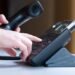 Une main appuie sur les touches d'un téléphone de bureau