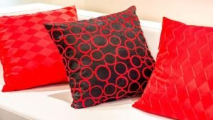 Trois coussins rouges et noirs aux motifs géométriques sur un canapé blanc