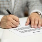 Homme écrivant sur un document avec un stylo noir à la table