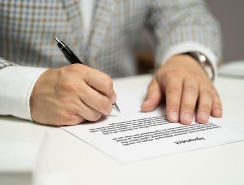 Homme écrivant sur un document avec un stylo noir à la table