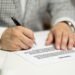 Homme écrivant sur un document avec un stylo noir à la table