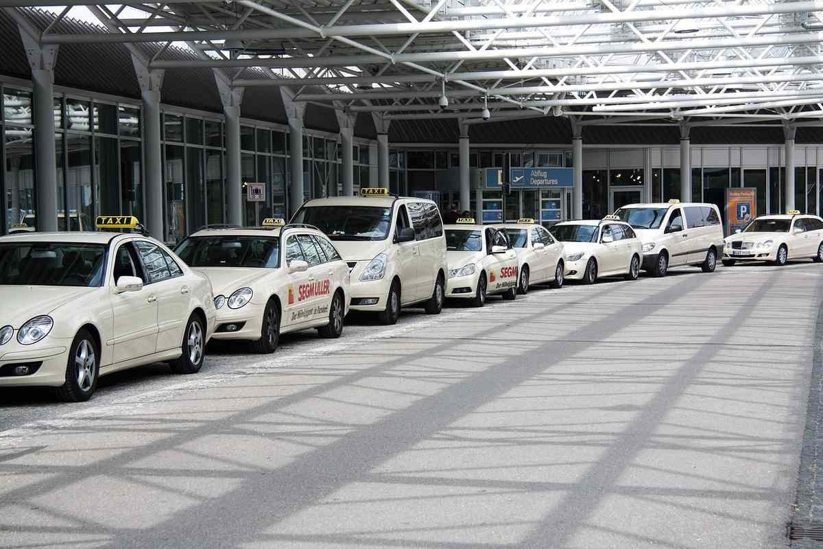 Une rangée de taxis blancs attendent devant le terminal de l'aéroport