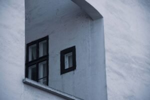 deux fenêtres noires sur façade blanche, aucune activité visible
