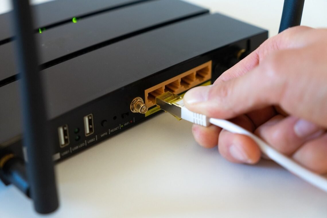 une main branche un câble Ethernet dans un routeur noir