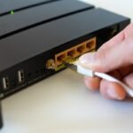 une main branche un câble Ethernet dans un routeur noir