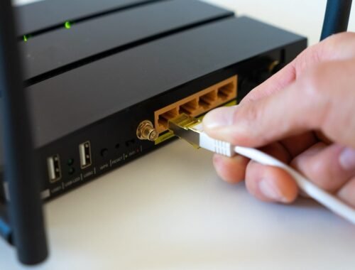 une main branche un câble Ethernet dans un routeur noir