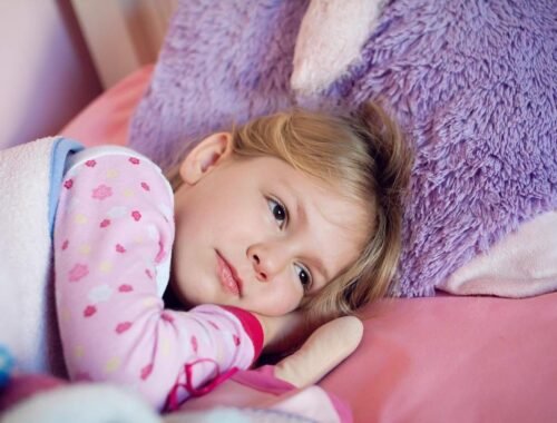 Une fillette blonde repose paisiblement sur un coussin rose