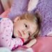 Une fillette blonde repose paisiblement sur un coussin rose