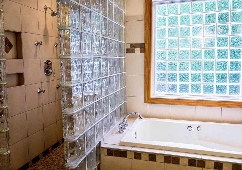 Salle de bain avec baignoire blanche, douche, et fenêtre en carreaux de verre coloré